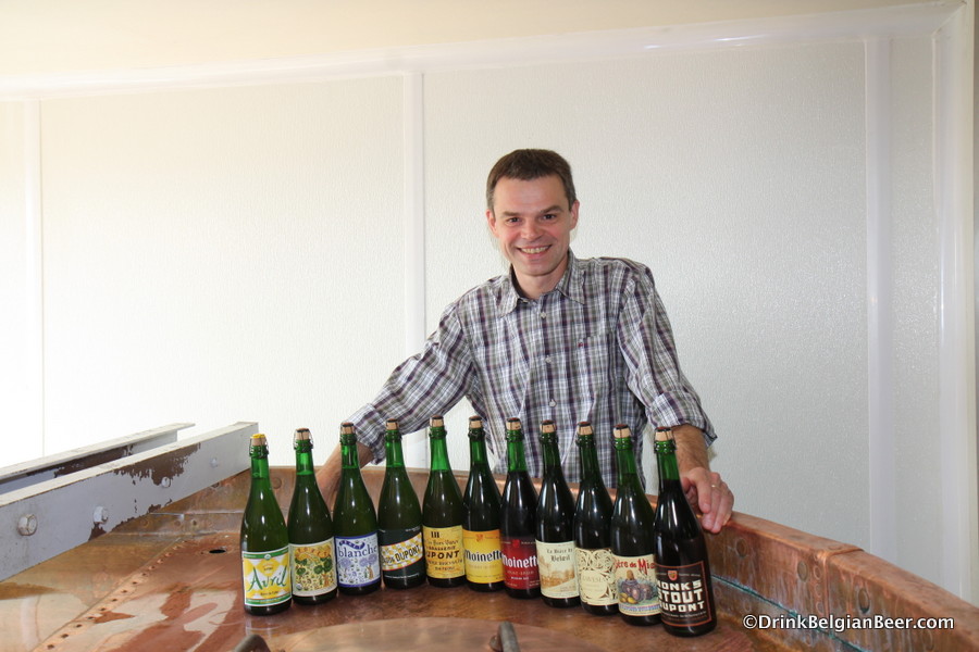 Brewmaster Olivier Dedeycker with some of his beers on top the copper boiling kettle at Brasserie Dupont. 