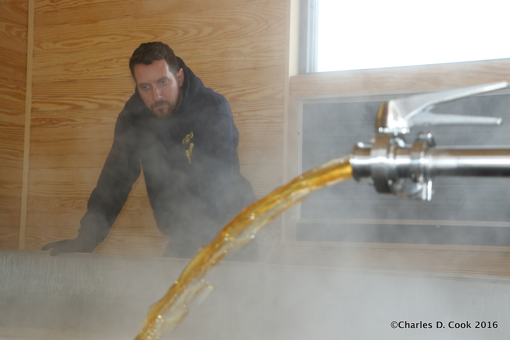 Brewer Matt Tarpey looks on as a stream of hot wort fills his coolship. 