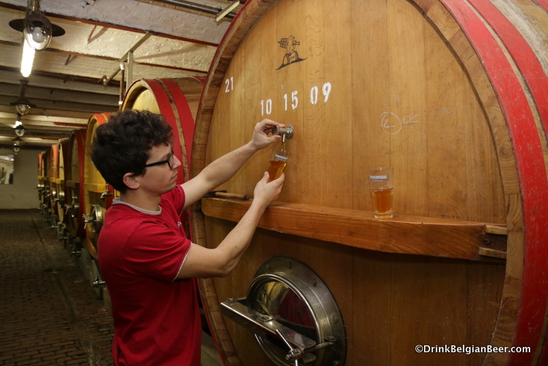 Brouwerij Timmermans brewer Kloris Deville pulling a glass of lambic from a foeder. 