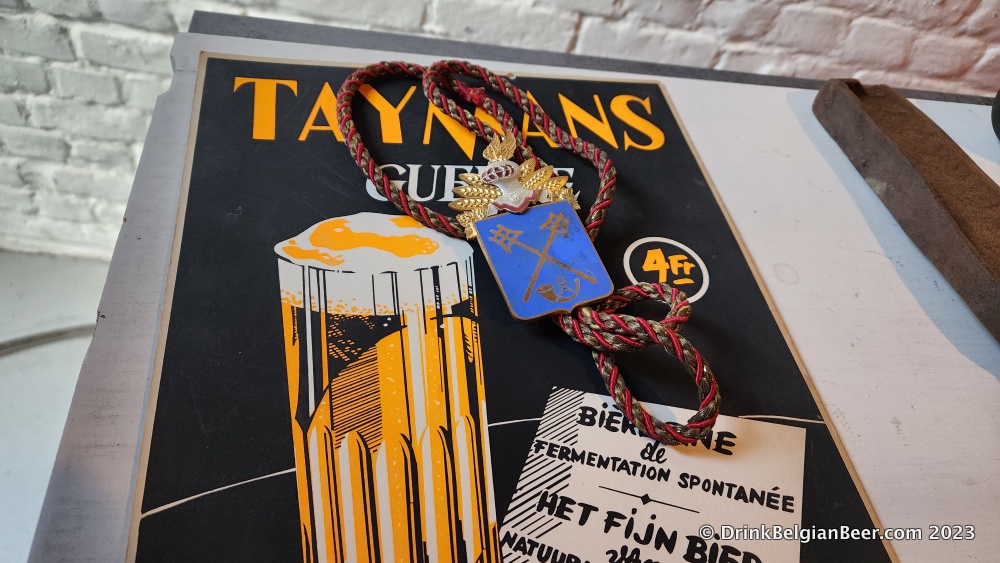 An old Taymans advertising poster, along with a medal of a Knight of the Brewer's Mash Staff.